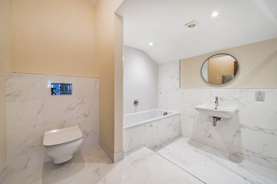 Modern bathroom with a toilet, bath and sink with mirror