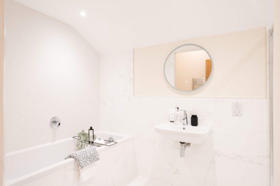Modern bright bathroom with a bath, sink and a mirror